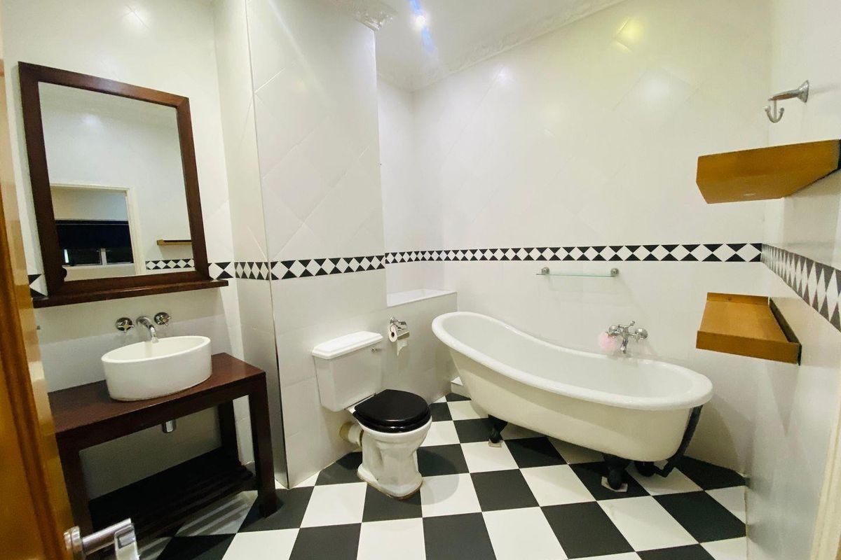 A well-maintained bathroom featuring a classic clawfoot bathtub, vessel sink vanity, and distinctive black and white checkered floor tiling.
