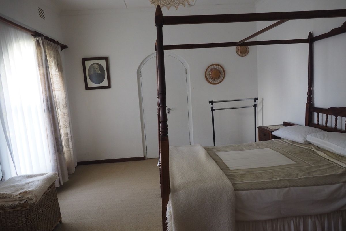 A spacious bedroom featuring neutral carpeting, an arched doorway, and large windows allowing for natural light.