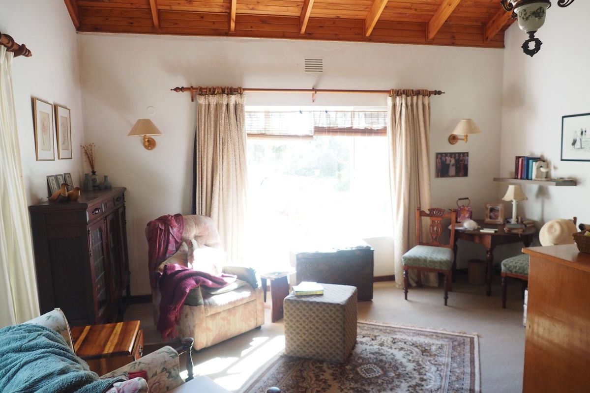 A cozy living room featuring a high vaulted timber-beamed ceiling and large window providing natural light.