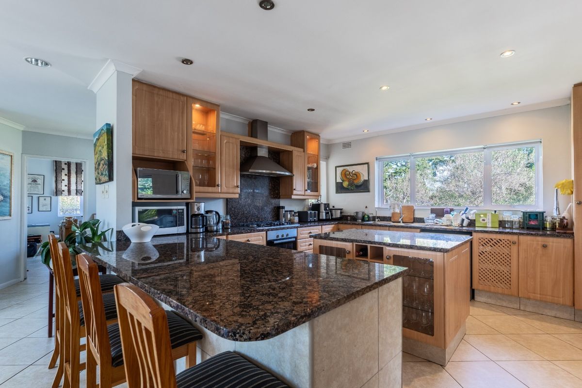 Spacious kitchen featuring granite countertops, a central island, wooden cabinetry, and built-in appliances, offering a functional layout with ample workspace.