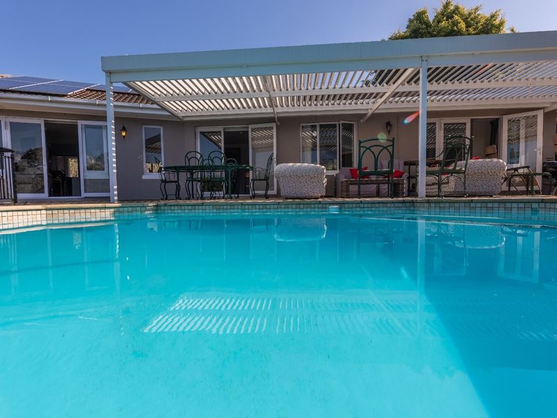 A well-maintained swimming pool area featuring a modern louvred patio roof, providing a seamless transition between the outdoor pool and the home's living spaces.