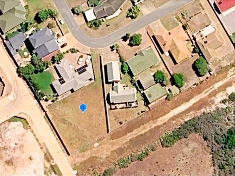 Aerial view of a vacant residential plot situated within an established suburban neighborhood, showing surrounding properties and access roads.
