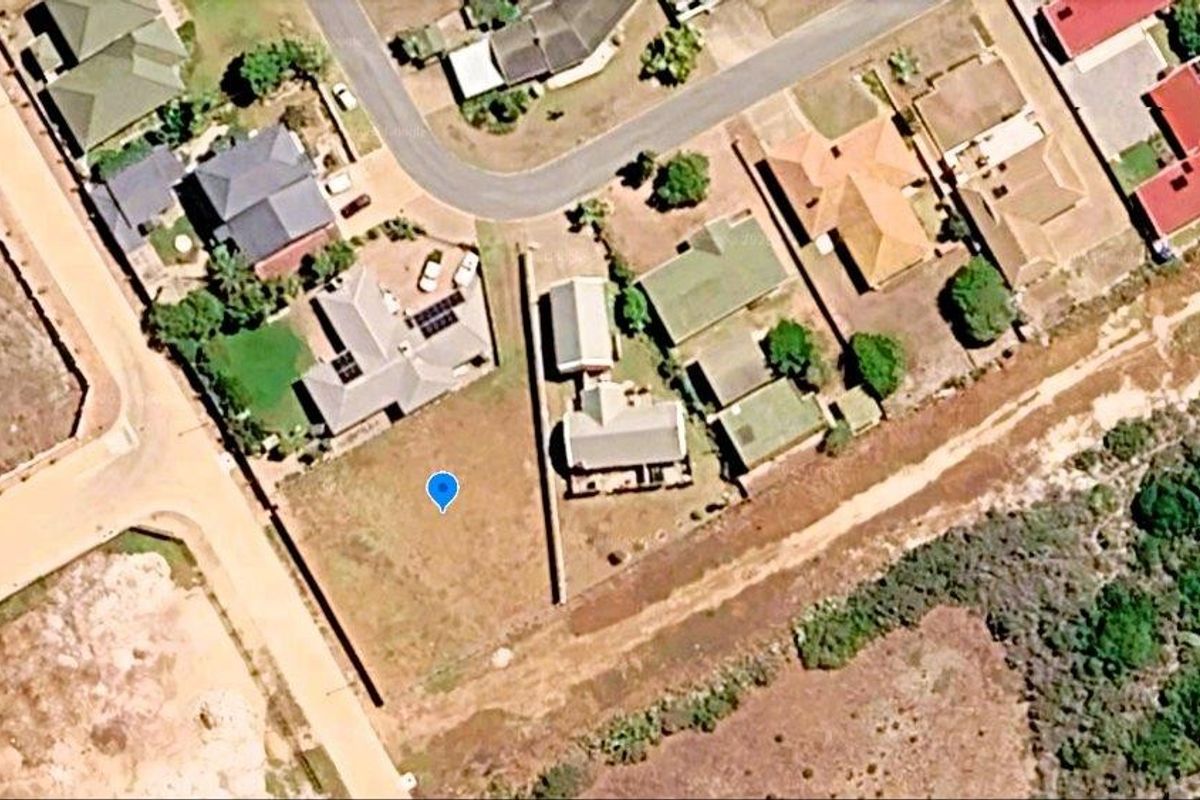 Aerial view of a vacant residential plot situated within an established suburban neighborhood, showing surrounding properties and access roads.