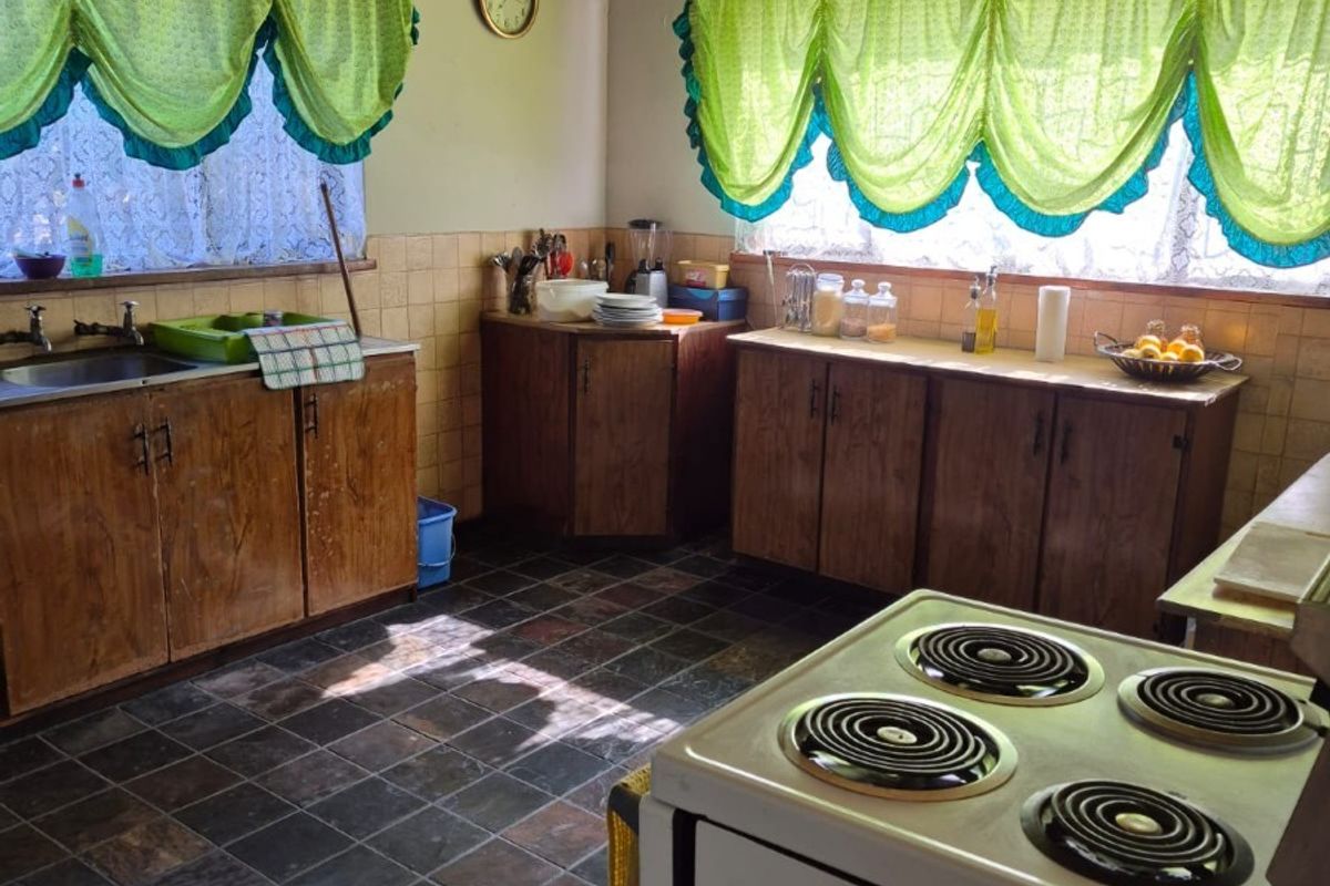 A dated kitchen featuring wood-finish cabinetry, slate-style floor tiles, and a timber-paneled ceiling, offering a functional layout with ample counter space.