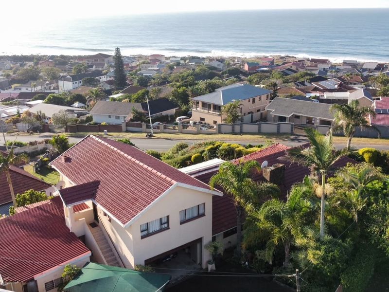 Aerial view of the property showing the tiled roof structure, surrounding garden, and coastal neighborhood setting.