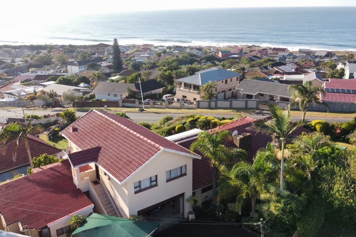 Aerial view of the property showing the tiled roof structure, surrounding garden, and coastal neighborhood setting.