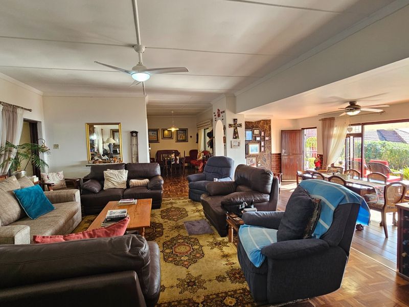 Spacious open-plan living and dining area featuring parquet flooring, a stone-clad fireplace, and large sliding doors leading to an outdoor patio.