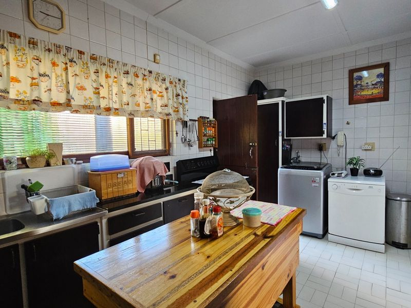 A functional kitchen featuring tiled walls, built-in cabinetry, a double sink, and dedicated space for laundry appliances.