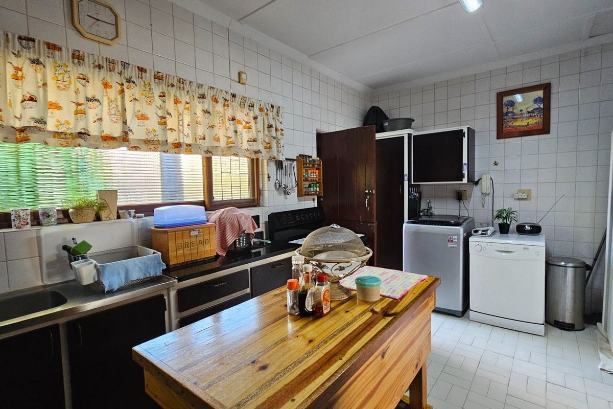 A functional kitchen featuring tiled walls, built-in cabinetry, a double sink, and dedicated space for laundry appliances.