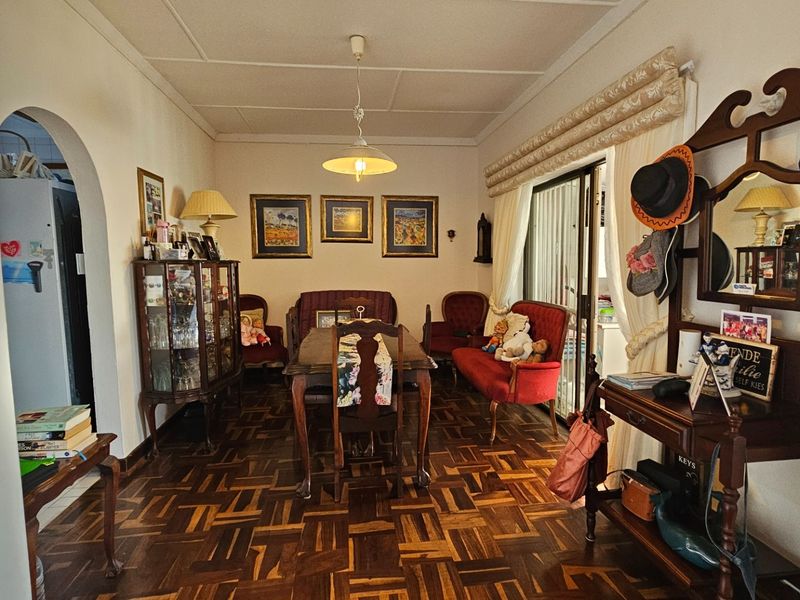 A traditional dining room featuring classic parquet wood flooring, an arched entryway, and sliding glass doors leading to an outdoor area.
