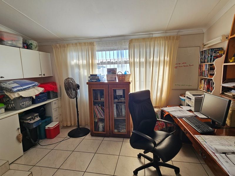A functional home office space featuring built-in cabinetry, a desk area, and tiled flooring, providing a dedicated workspace within the home.