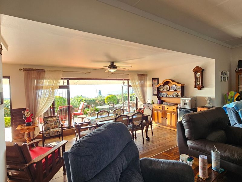 Spacious open-plan living and dining area featuring parquet flooring, a ceiling fan, and large sliding doors opening onto an outdoor patio.