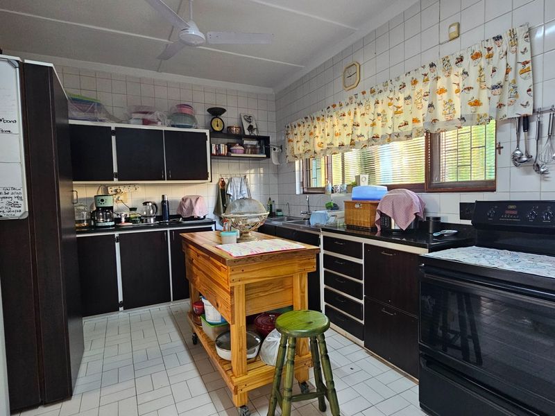 A functional kitchen featuring dark cabinetry, black countertops, a built-in oven, and tiled walls, offering a practical layout for daily meal preparation.