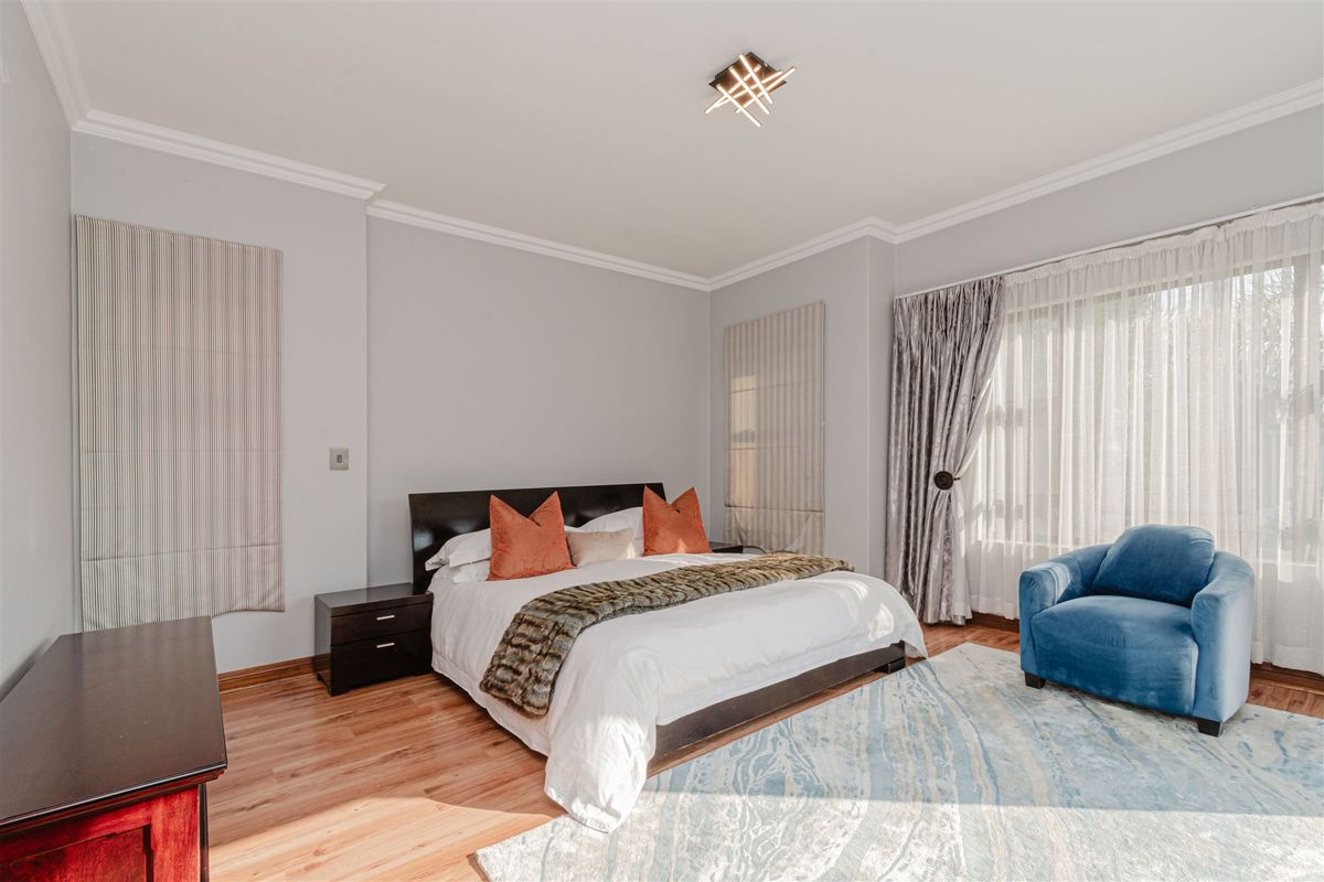 A well-maintained bedroom featuring hardwood flooring, crown molding, and a modern ceiling light fixture, offering a bright and comfortable living space.