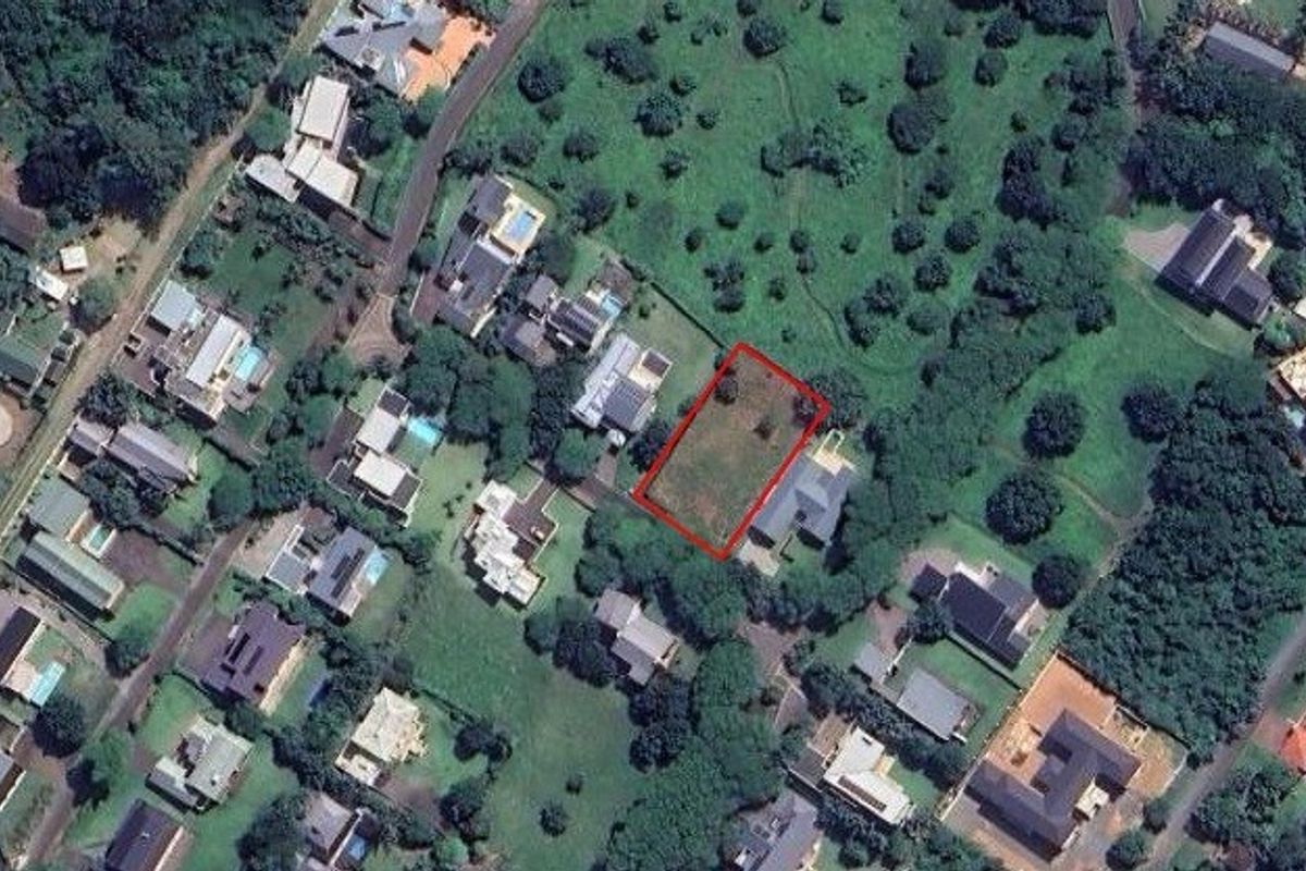 Aerial view of a vacant residential plot highlighted in red, situated within a developed suburban neighborhood with established greenery.