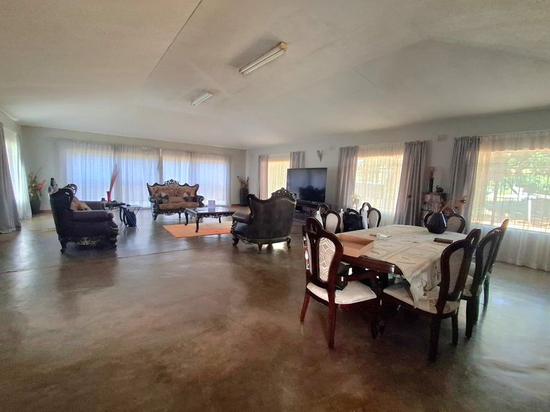Spacious open-plan living and dining area featuring polished concrete flooring, large windows with natural light, and functional overhead lighting.