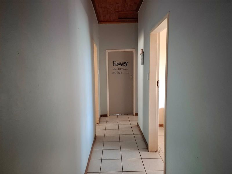 A functional interior hallway featuring tiled flooring and a wooden ceiling, providing access to multiple rooms within the property.