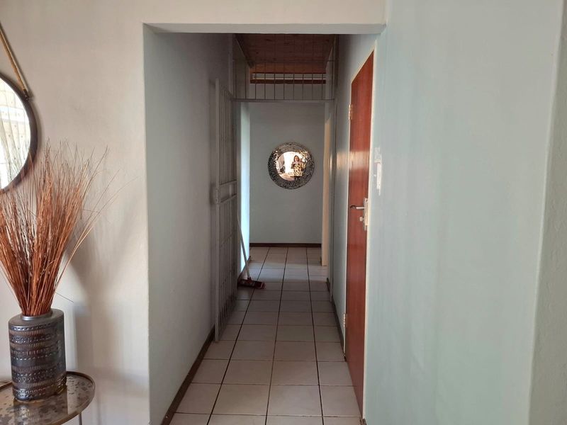 A functional interior hallway featuring tiled flooring, a security gate, and access to adjacent rooms.