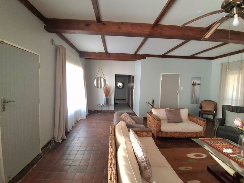 Spacious living area featuring exposed timber ceiling beams, terracotta tiled flooring, and direct access to the hallway.