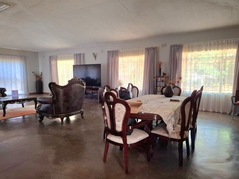 Spacious open-plan living and dining area featuring large windows, neutral walls, and polished concrete flooring, offering a versatile layout for family living.