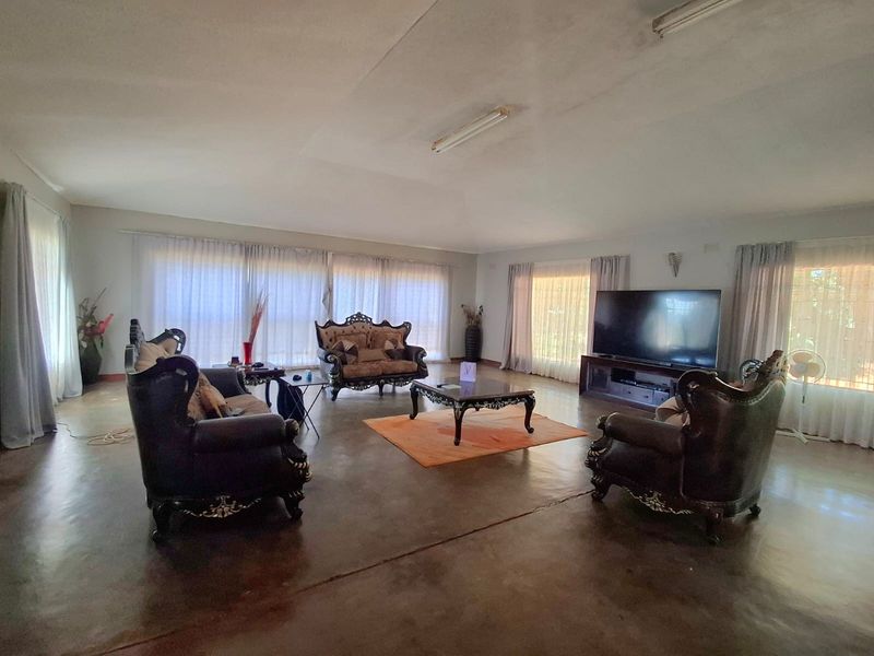 Spacious living room featuring large windows with natural light, neutral walls, and polished concrete flooring, offering a versatile open-plan layout.