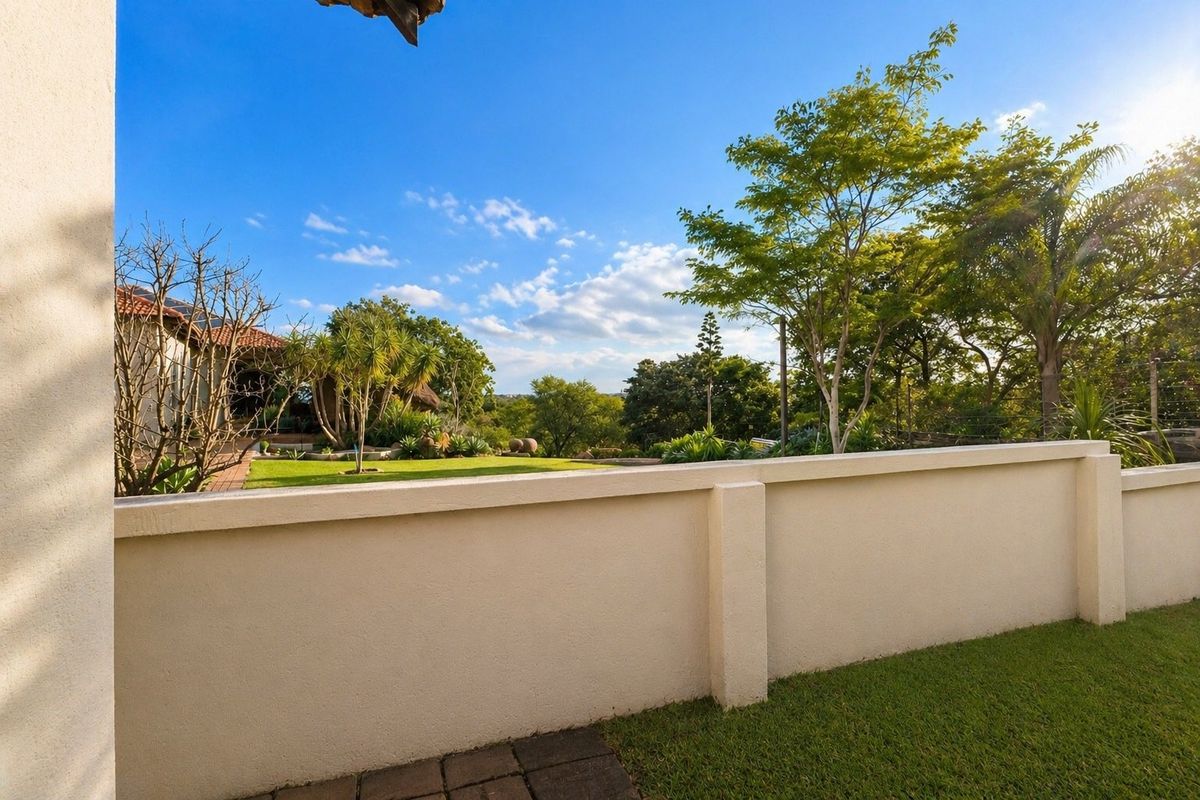 A well-maintained rear garden featuring a solid boundary wall, lush lawn, and mature trees with a pleasant outlook.