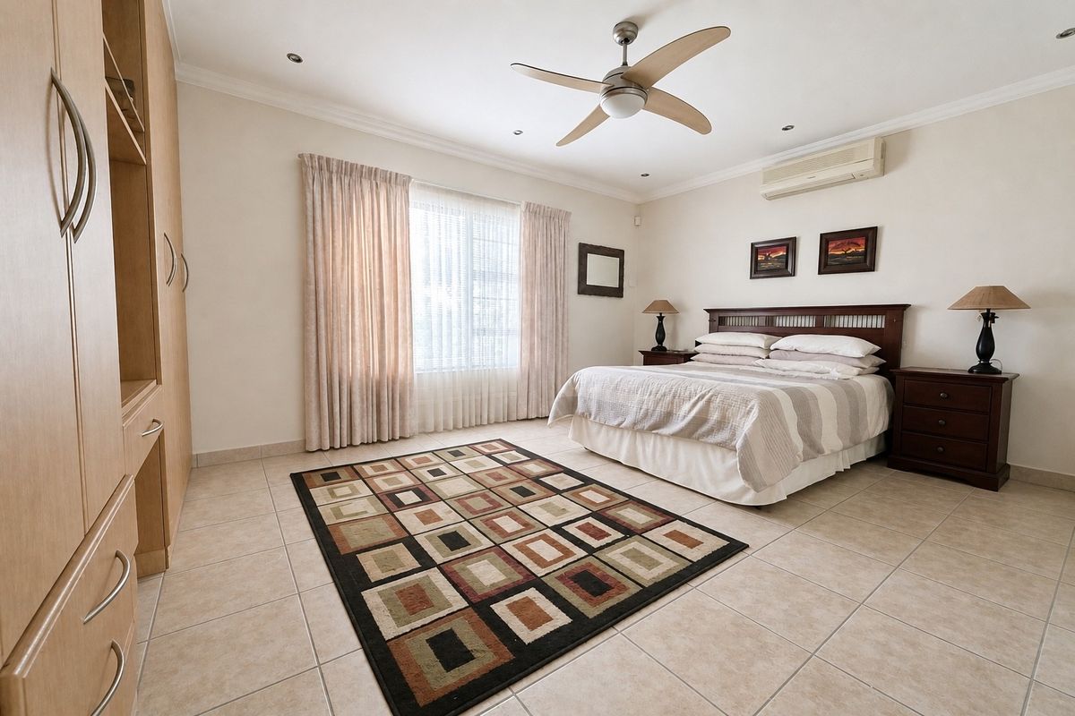 Spacious bedroom featuring neutral tiled flooring, built-in cabinetry, a ceiling fan, and a wall-mounted air conditioning unit.