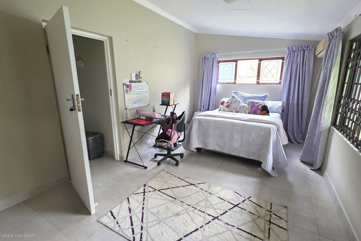 A functional bedroom featuring tiled flooring, security bars on windows, and a wall-mounted air conditioning unit.