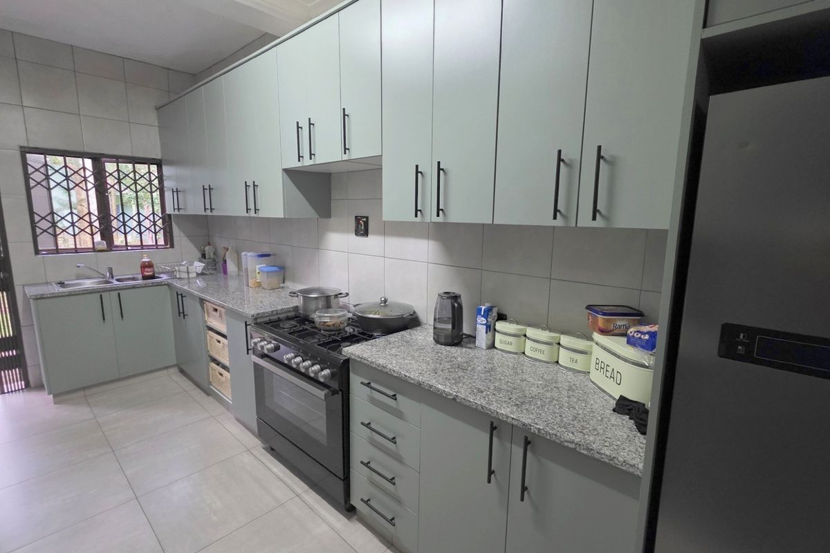 Modern kitchen featuring light green cabinetry, granite countertops, tiled backsplash, and a built-in gas stove with an oven.