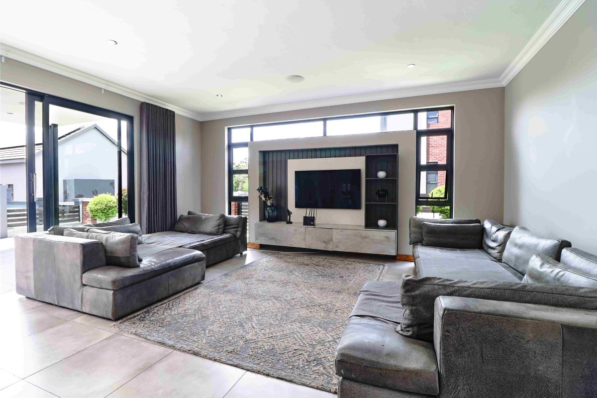 Spacious living room featuring large sliding glass doors, tiled flooring, and a custom built-in media wall with integrated shelving and cabinetry.