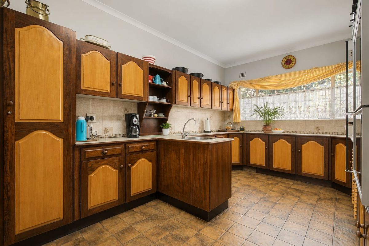 A traditional kitchen featuring two-tone wooden cabinetry, tiled splashbacks, and tiled flooring, offering ample storage and counter space.