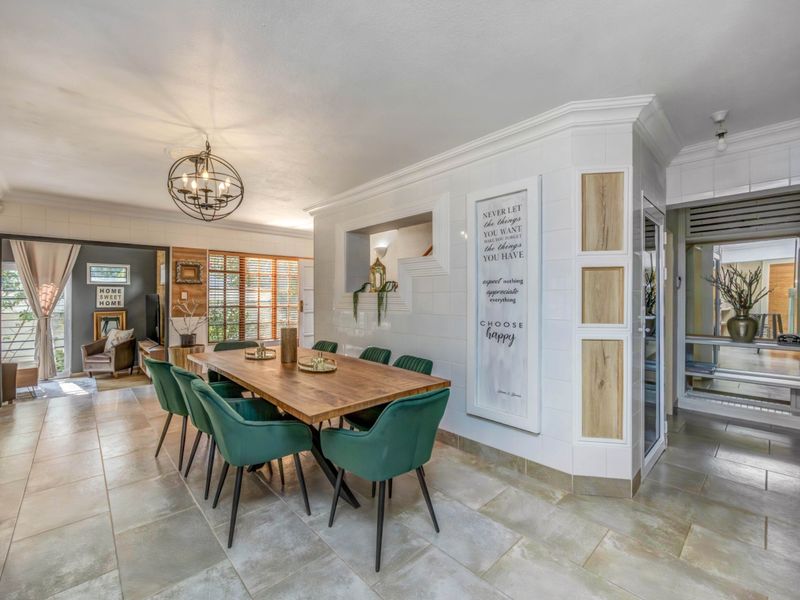 Spacious open-plan dining area featuring tiled flooring, decorative wall paneling, and a built-in feature niche, seamlessly connecting to adjacent living spaces.