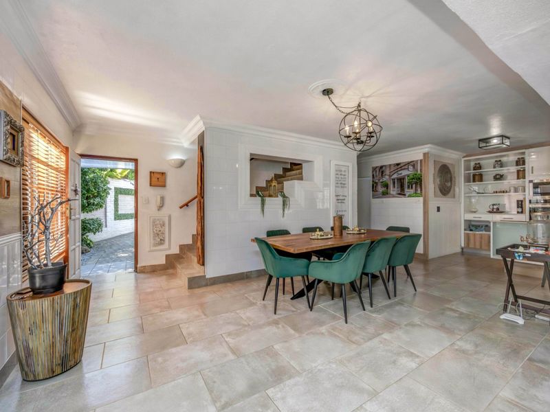Spacious open-plan dining area featuring large format floor tiles, built-in shelving, and direct access to the exterior entrance.