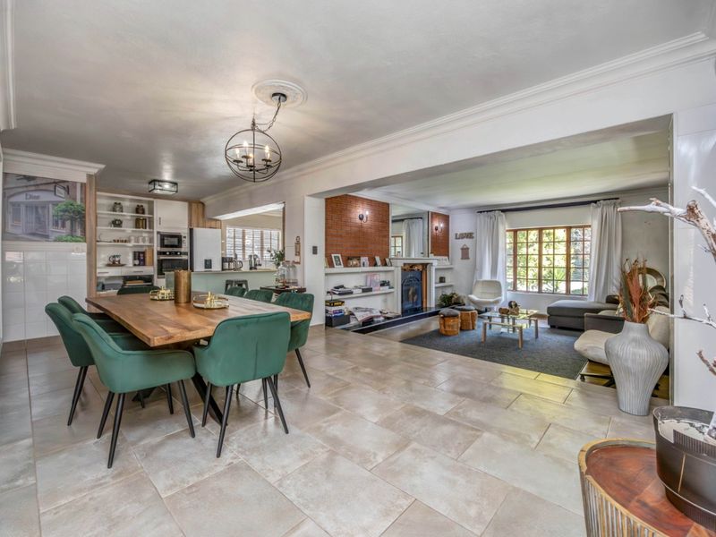 Spacious open-plan living and dining area featuring tiled flooring, a built-in fireplace with brick detailing, and a modern kitchen with integrated cabinetry.