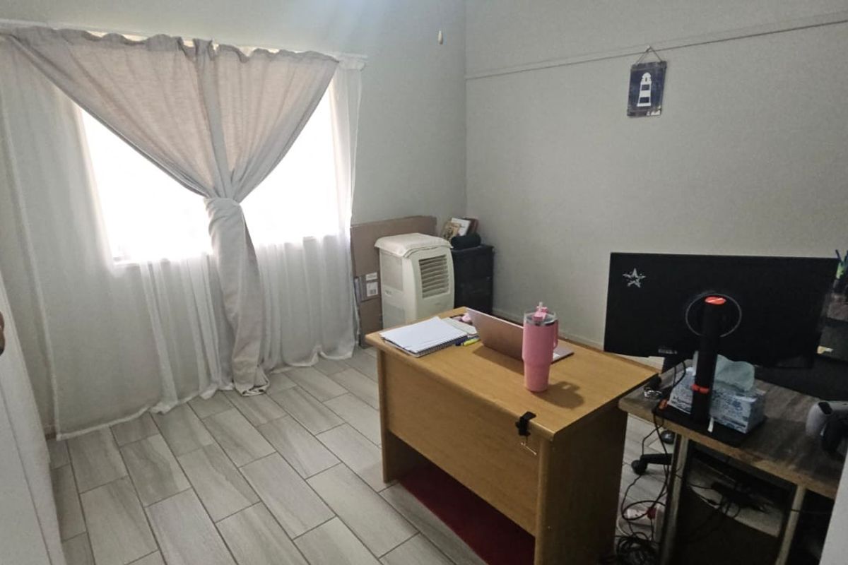 A functional bedroom featuring tiled flooring and a built-in cupboard, currently utilized as a home office space.