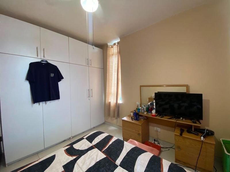 A bedroom featuring built-in floor-to-ceiling white cabinetry and tiled flooring, providing ample storage space.