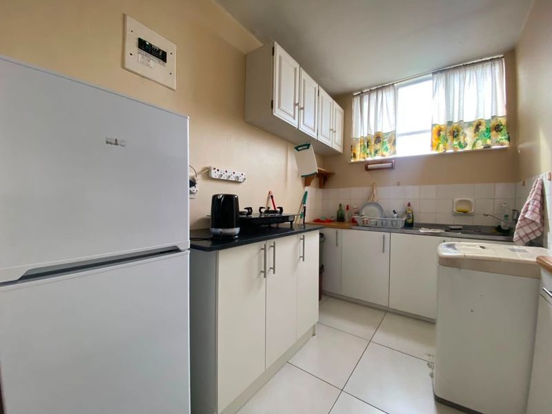 Compact kitchen featuring white cabinetry, tiled flooring, and a functional layout with integrated sink and counter space.