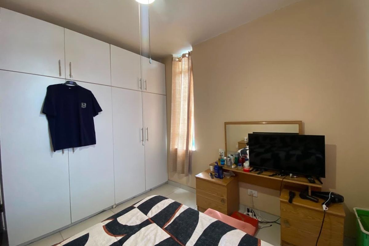 A bedroom featuring built-in floor-to-ceiling white cabinetry and tiled flooring, providing ample storage space.