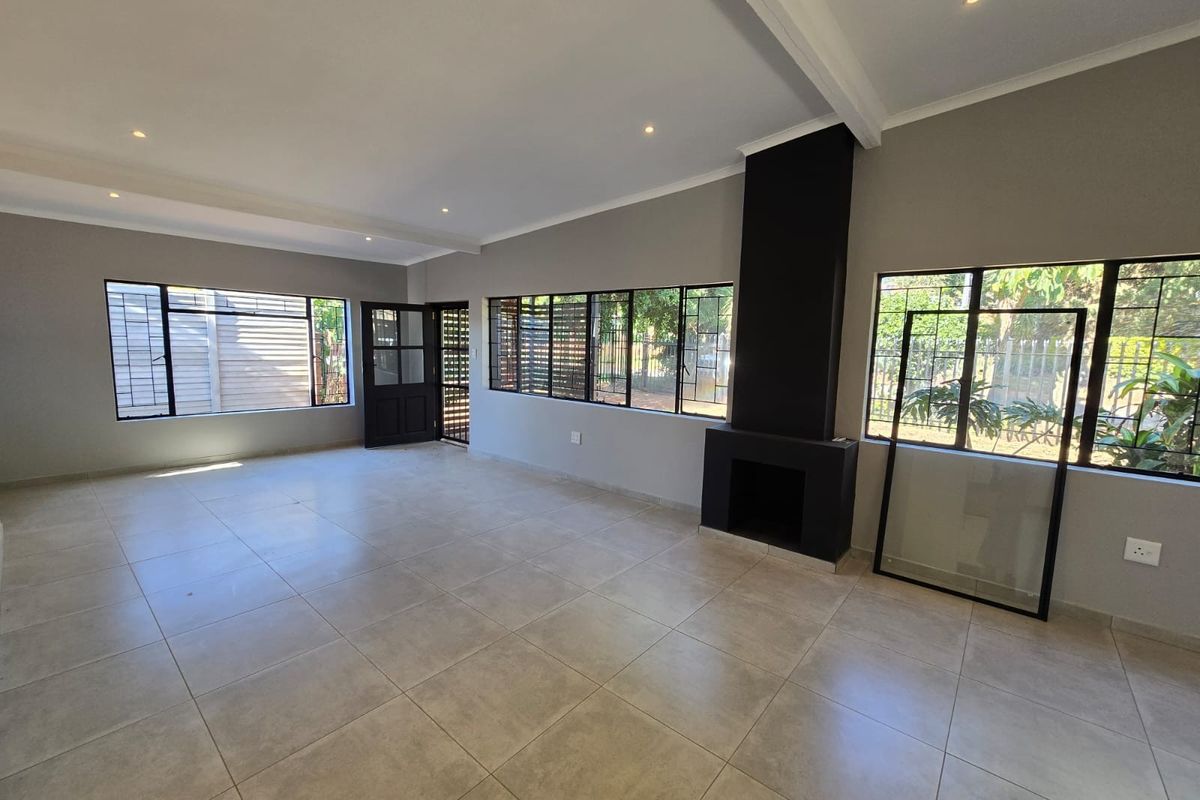 Spacious open-plan living area featuring neutral floor tiles, recessed ceiling lighting, and a modern black built-in fireplace.