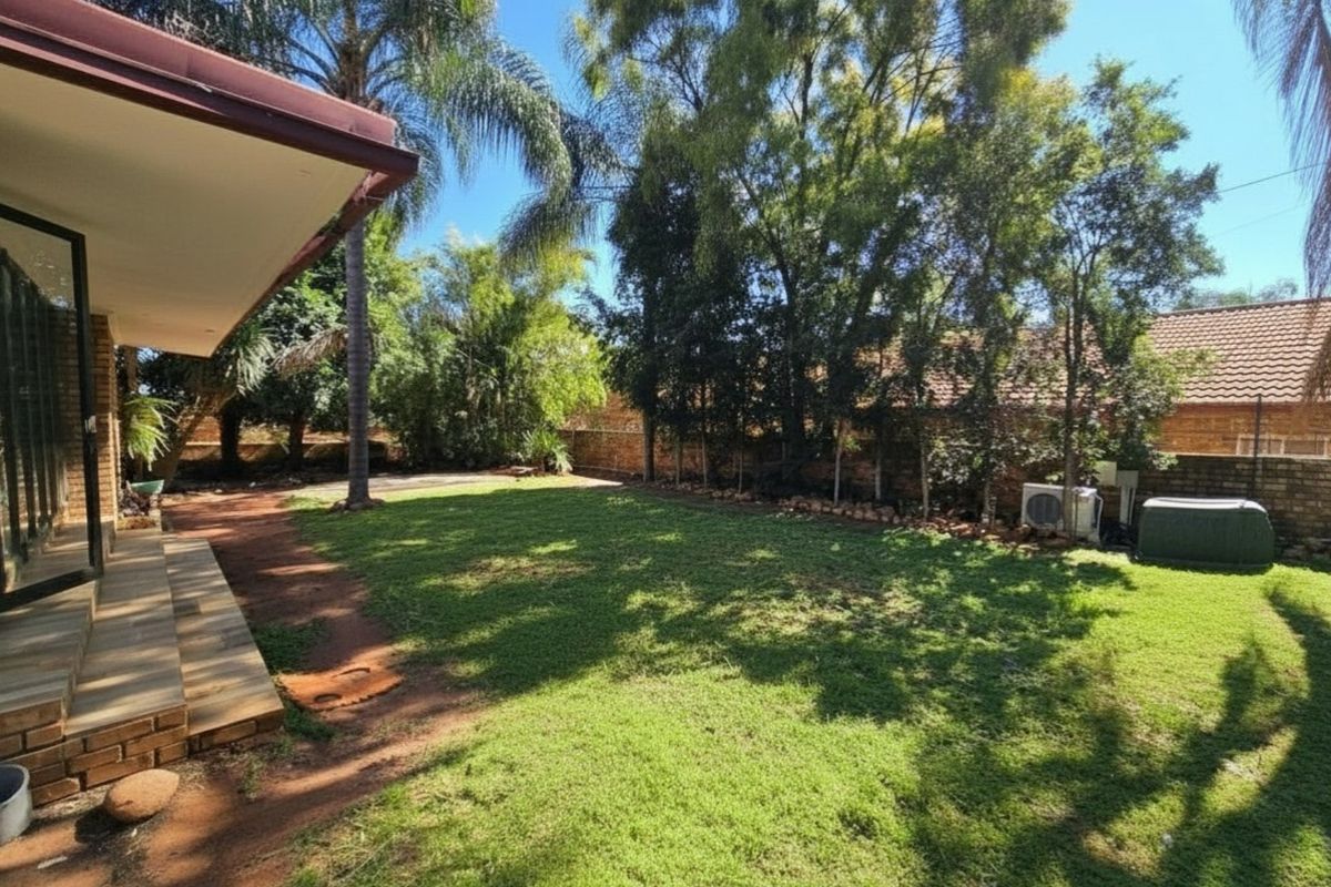 A spacious rear garden featuring a manicured lawn, mature trees, and a covered patio area, providing a private outdoor space for relaxation.