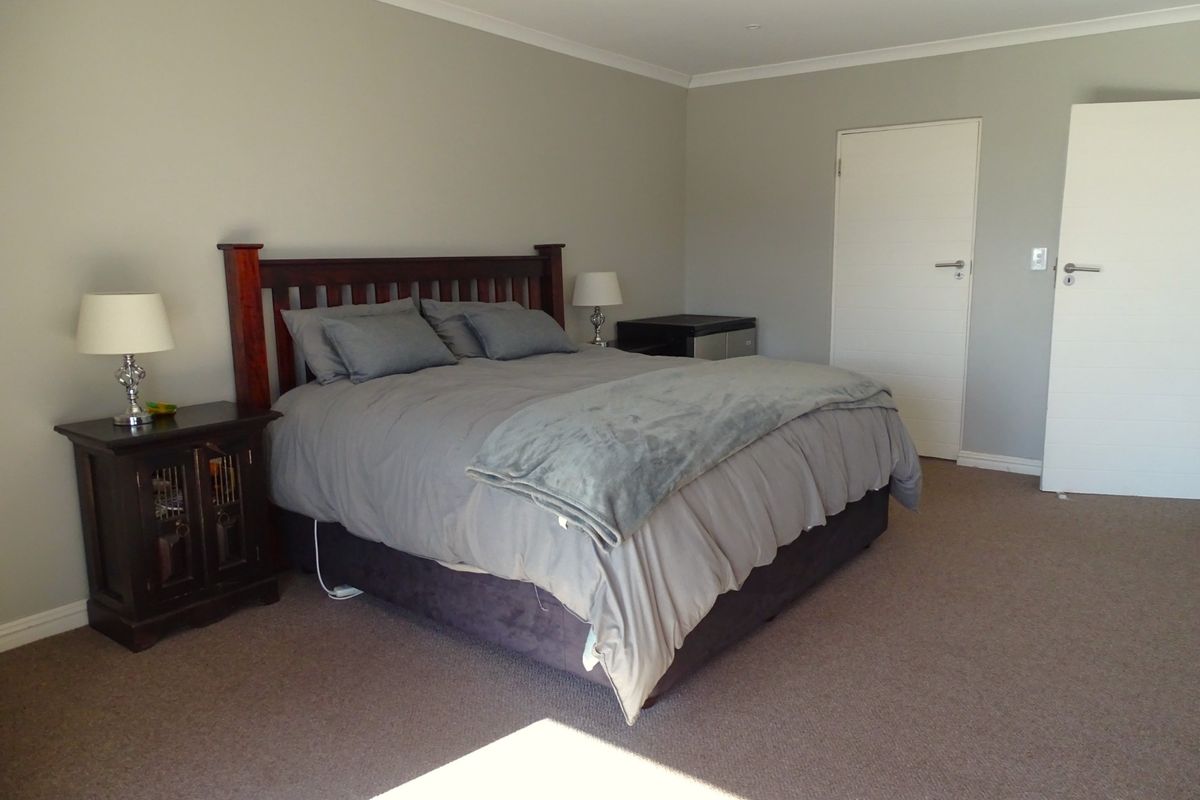 A spacious bedroom featuring neutral wall tones, plush carpeting, and two white interior doors.