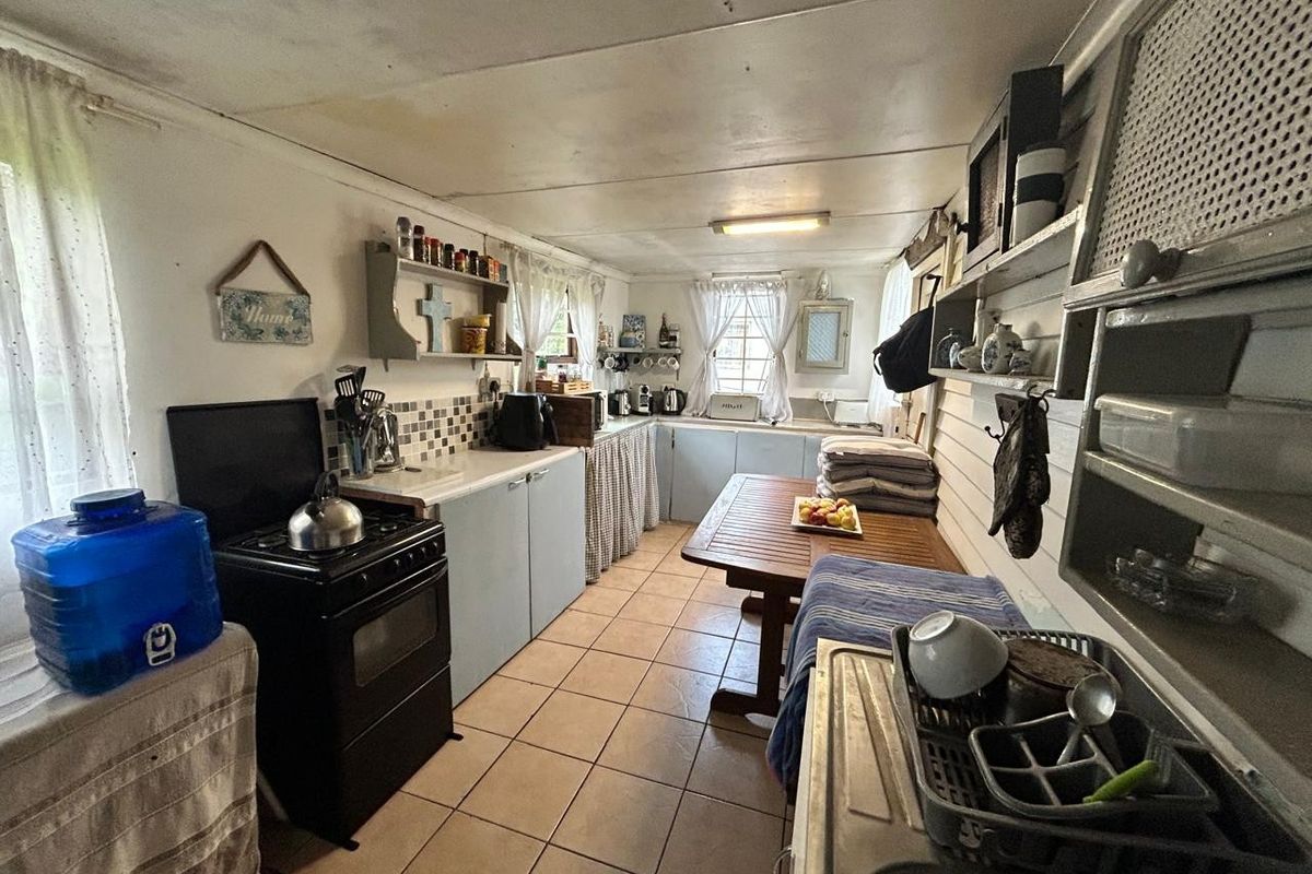 A functional kitchen featuring tiled flooring, built-in cabinetry, and a freestanding stove, offering a practical layout with potential for modernization.