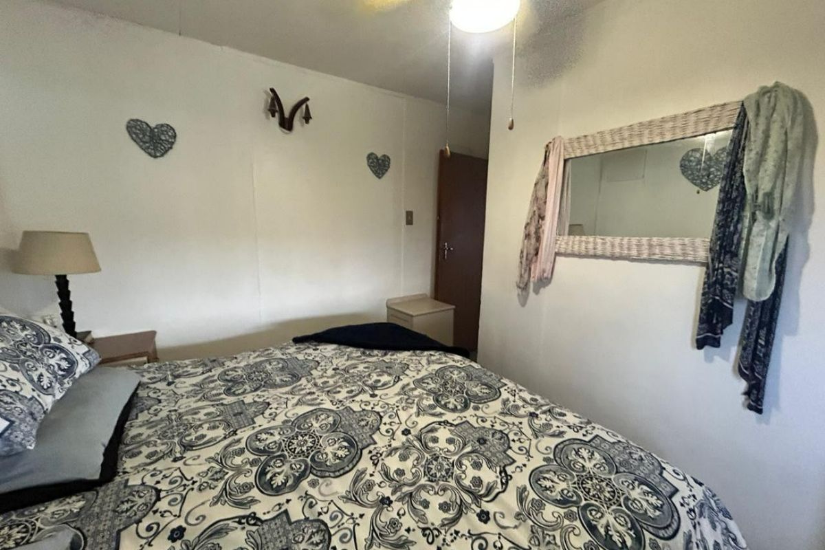 A compact bedroom featuring a ceiling fan and standard interior door, providing a functional sleeping space.