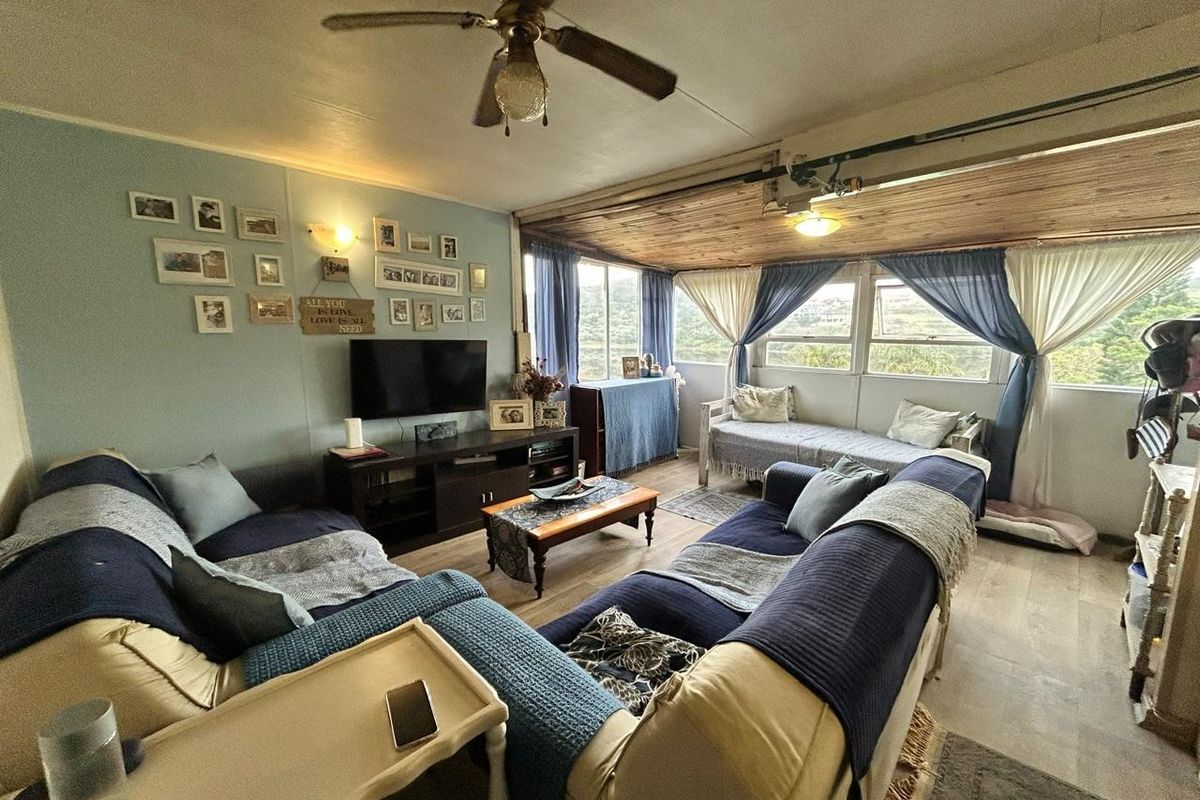A comfortable living room featuring wood-paneled ceilings, large windows with natural light, and durable flooring, creating a relaxed and inviting atmosphere.