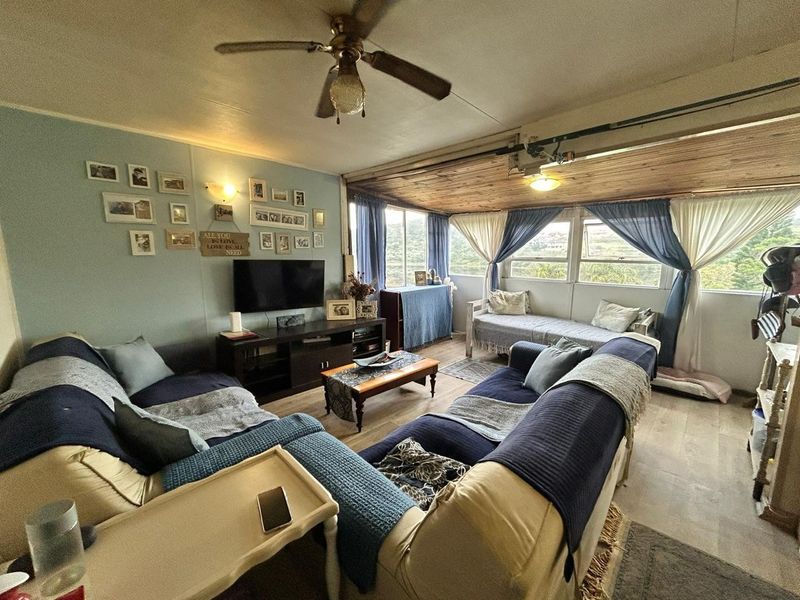 A comfortable living room featuring wood-paneled ceilings, large windows with natural light, and durable flooring, creating a relaxed and inviting atmosphere.