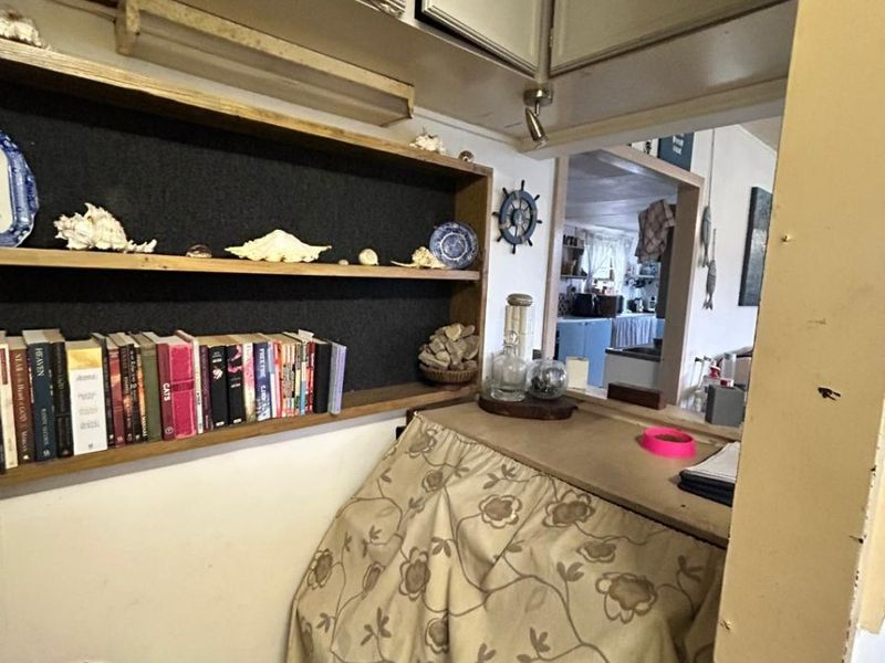 A small utility or pantry area featuring built-in overhead cabinetry and open shelving, providing functional storage space adjacent to the main living area.