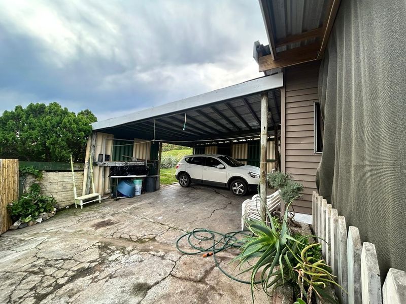 A covered outdoor carport area featuring a concrete slab floor and corrugated metal roof structure attached to the side of the house.