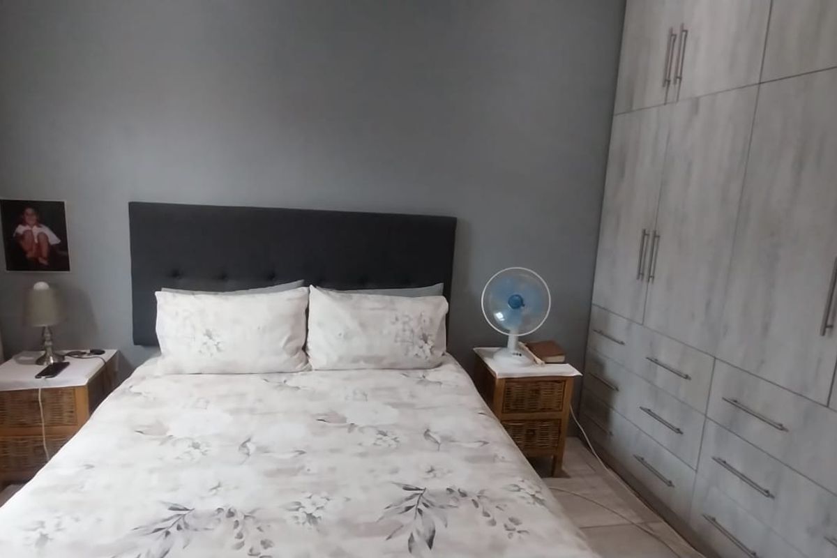 A well-maintained bedroom featuring extensive built-in cabinetry with a modern wood-grain finish and neutral wall tones.