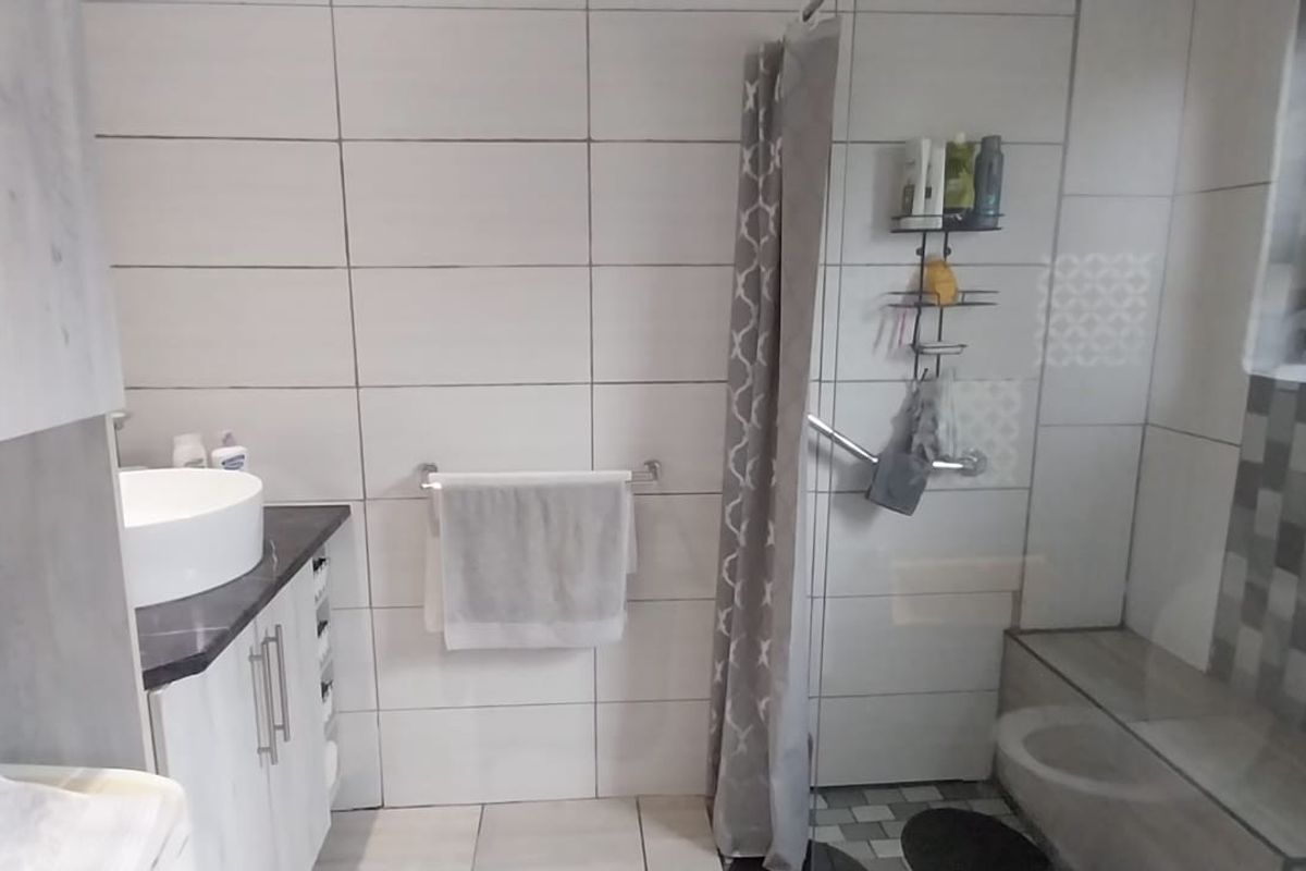 A functional bathroom featuring a modern vessel sink vanity, tiled walls, and a walk-in shower area with a built-in bench seat.