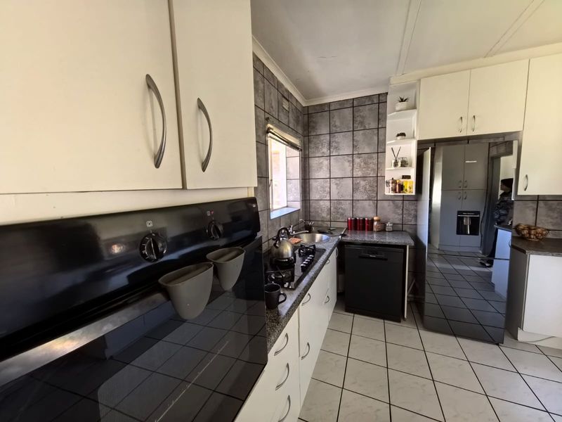 A functional kitchen featuring built-in cabinetry, granite countertops, a gas hob, and a tiled splashback, offering a practical layout for daily meal preparation.